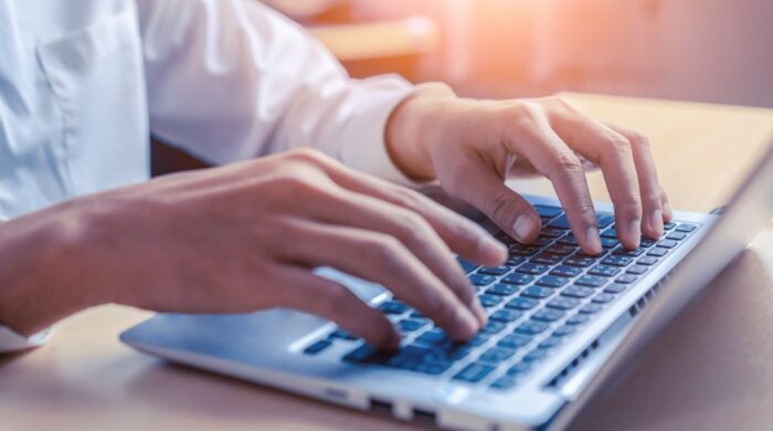 Businessman hand typing on computer keyboard of a laptop computer in office. Business and finance concept.